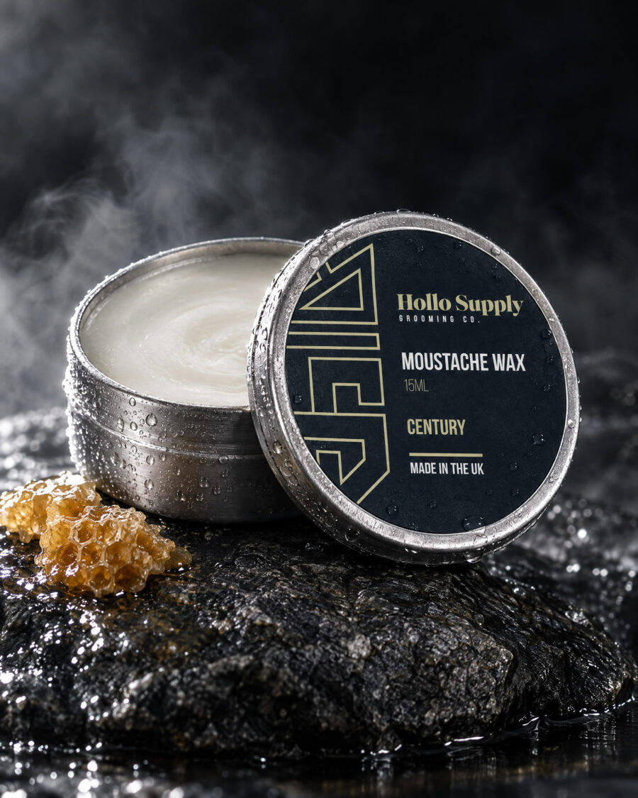 Moustache Wax (Century) by Hollo Supply Grooming Co., photographed on wet charcoal stone with water