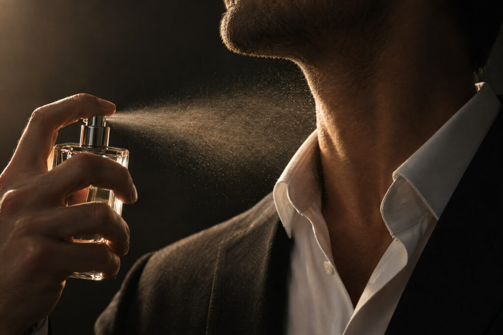 Man spraying cologne towards his neck