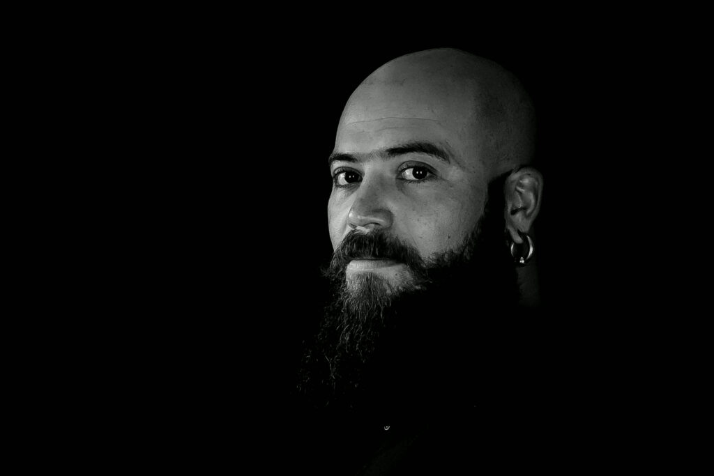 Black and white portrait of a bearded man against a dark background
