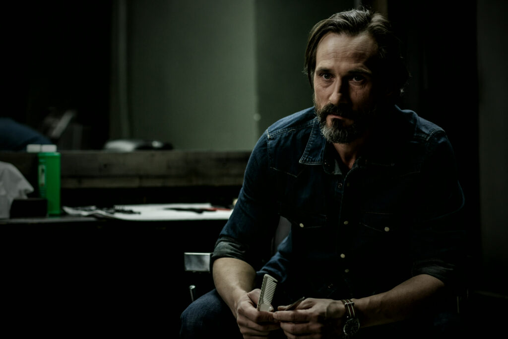 Bearded man sitting in a dimly lit barbershop