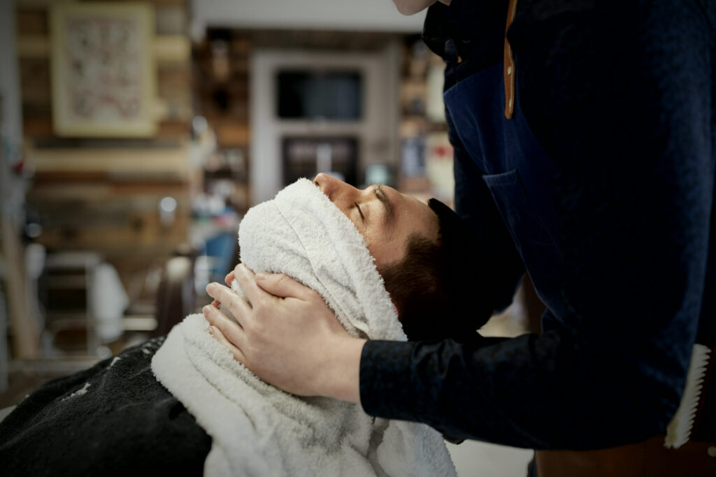 Barber applying a hot towel before a traditional shave