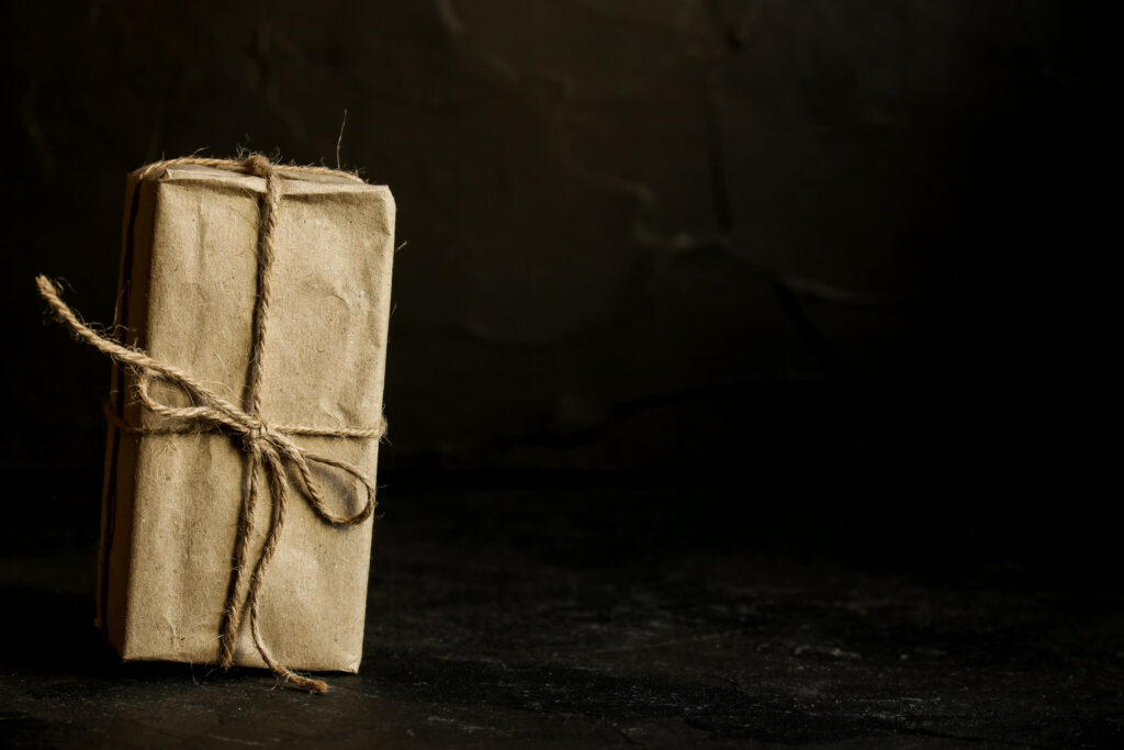 A small gift wrapped in brown kraft paper and tied with twine on a dark stone surface