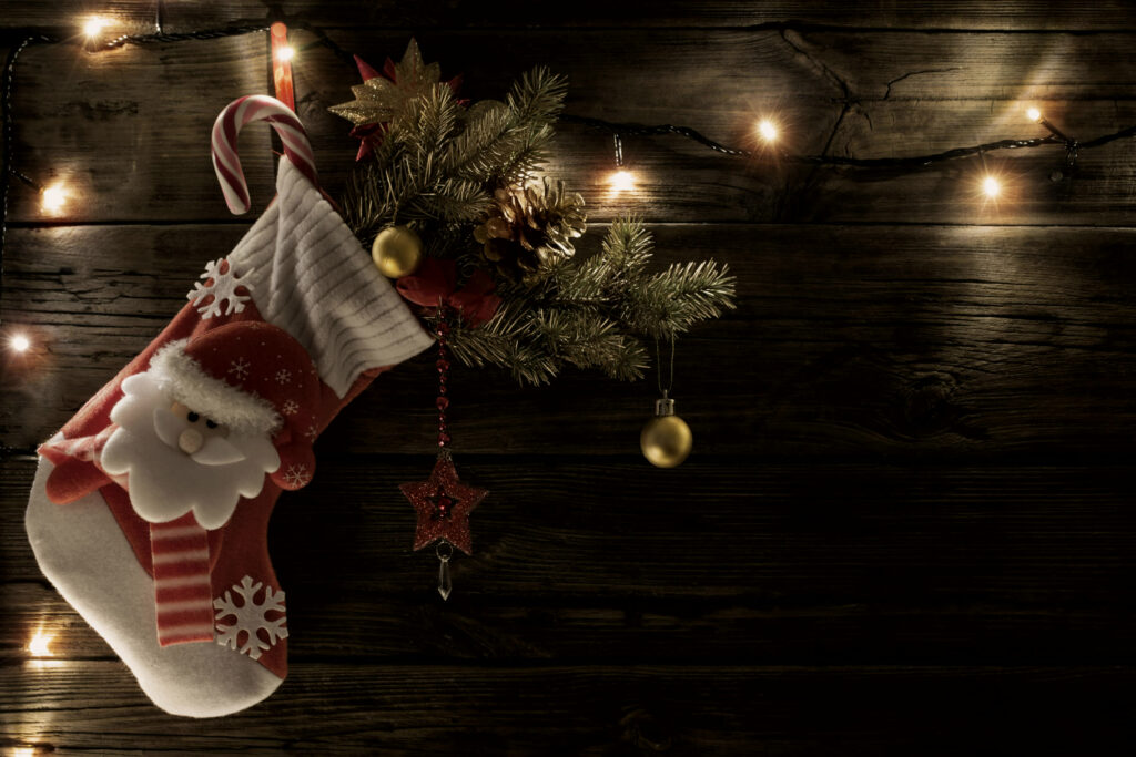 Christmas stocking filled with small gifts hanging against a dark, weathered wooden wall